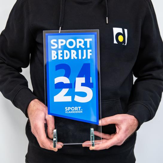 Iemand van de sportdienst houdt de trofee 'Sportbedrijf' vast 